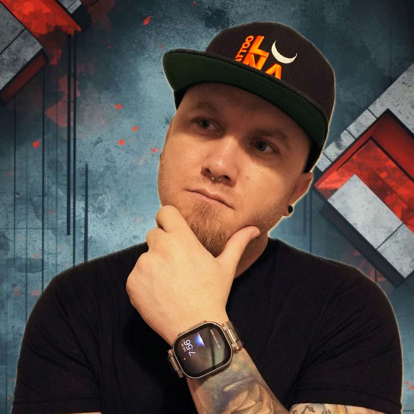 Man in a black cap and T-shirt posing thoughtfully with hand on chin, showing a smartwatch and tattooed arm